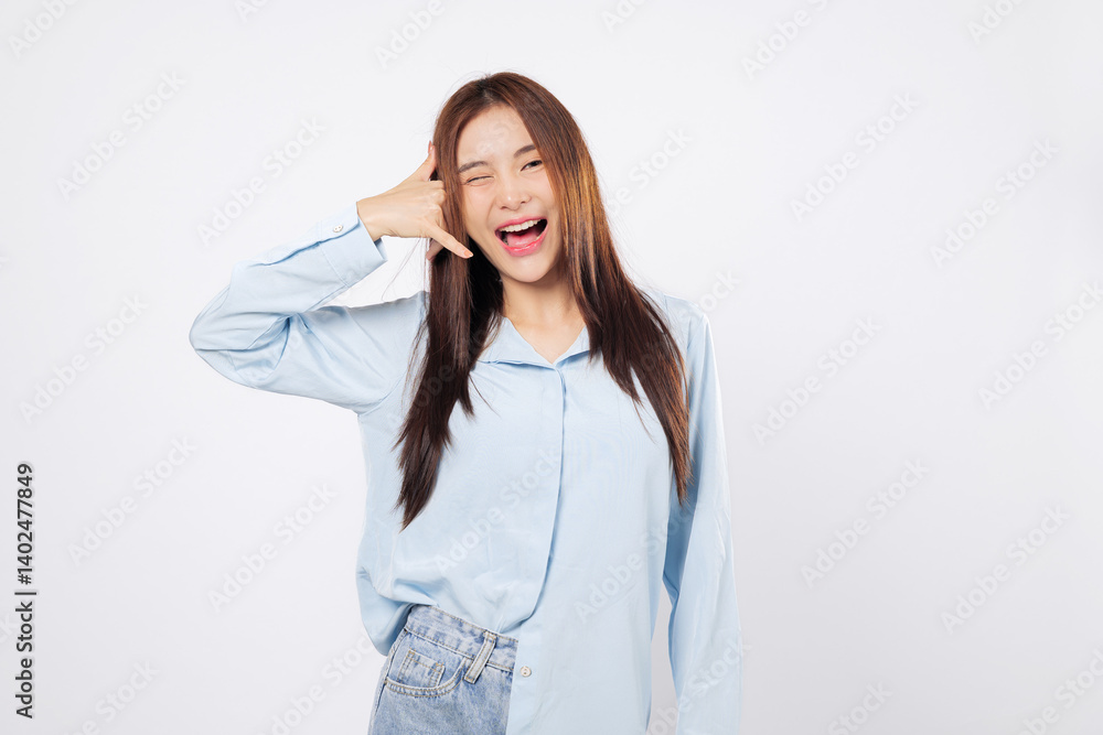 Woman making call me gesture with fingers, another woman smiles winking while mimicking a phone with hand near face, playful studio pose isolated on white background. Woman making call me gesture with fingers, another woman smiles winking while mimicking a phone with hand near face, playful studio pose isolated on white background.