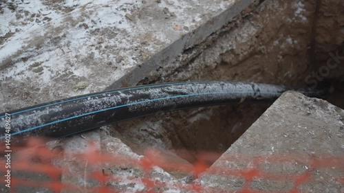 Thick rubber hose extends into sewer pit as maintenance work continues. Utility workers ensure system stays functional. Preventing clogs and overflows