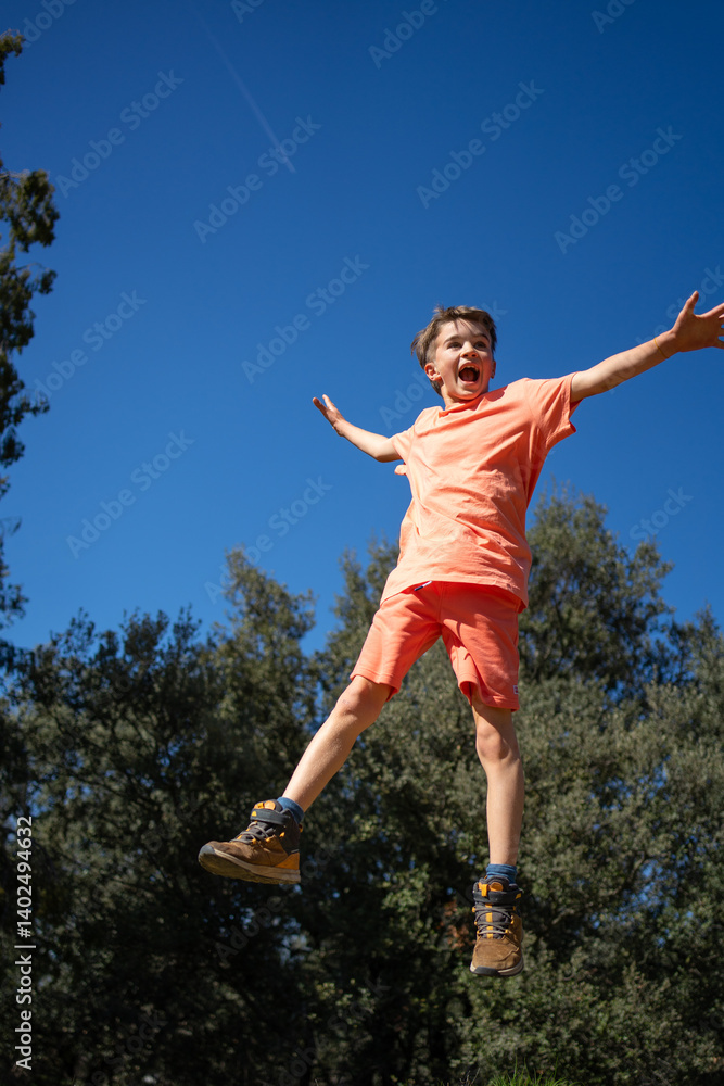 Excited boy jumping with open arms and screaming in a park