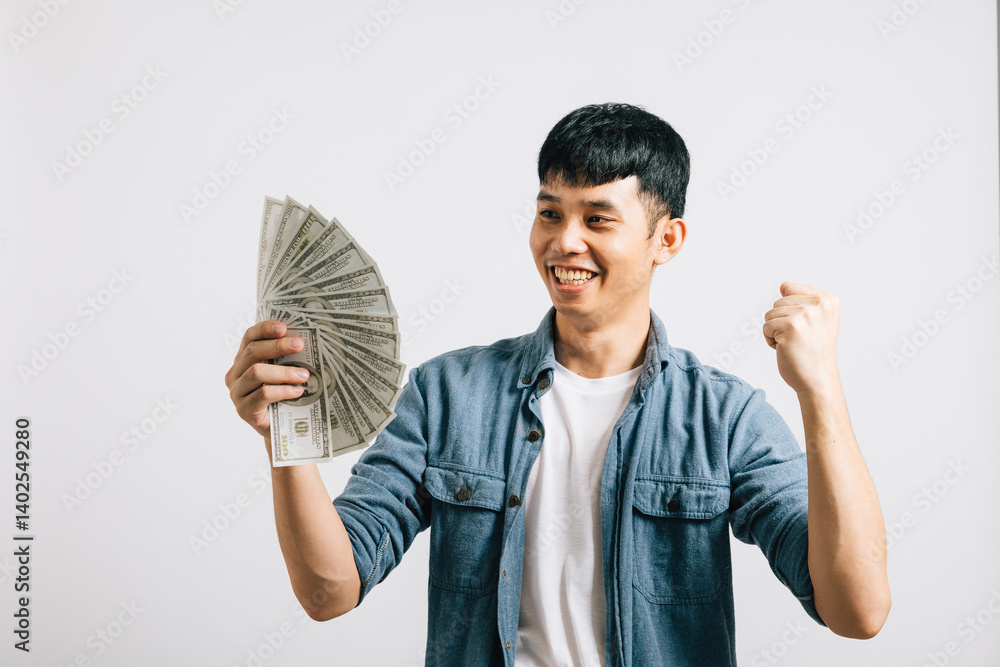 Portrait smiling Asian young man holding a bunch of money and pointing studio shot isolated white background, happiness and excitement man in dollar banknotes celebrating his financial success