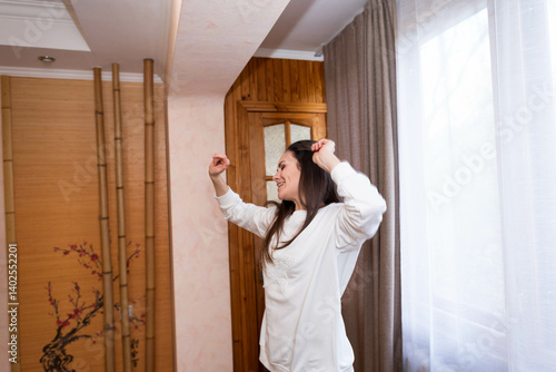 Happy, energetic girl in a white sweatshirt and black leggings dancing at home