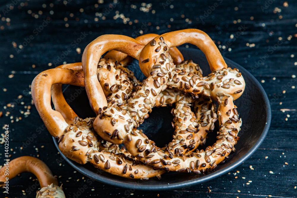 Fresh prepared homemade soft pretzels. Different types of baked pretzels with seeds on a black background
