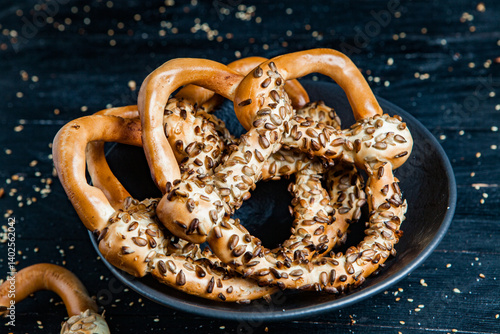 Obraz na płótnie Fresh prepared homemade soft pretzels. Different types of baked pretzels with seeds on a black background w salonie