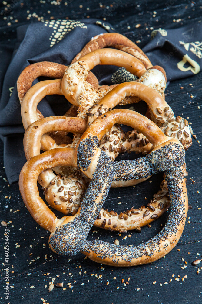 Fresh prepared homemade soft pretzels. Different types of baked pretzels with seeds on a black background