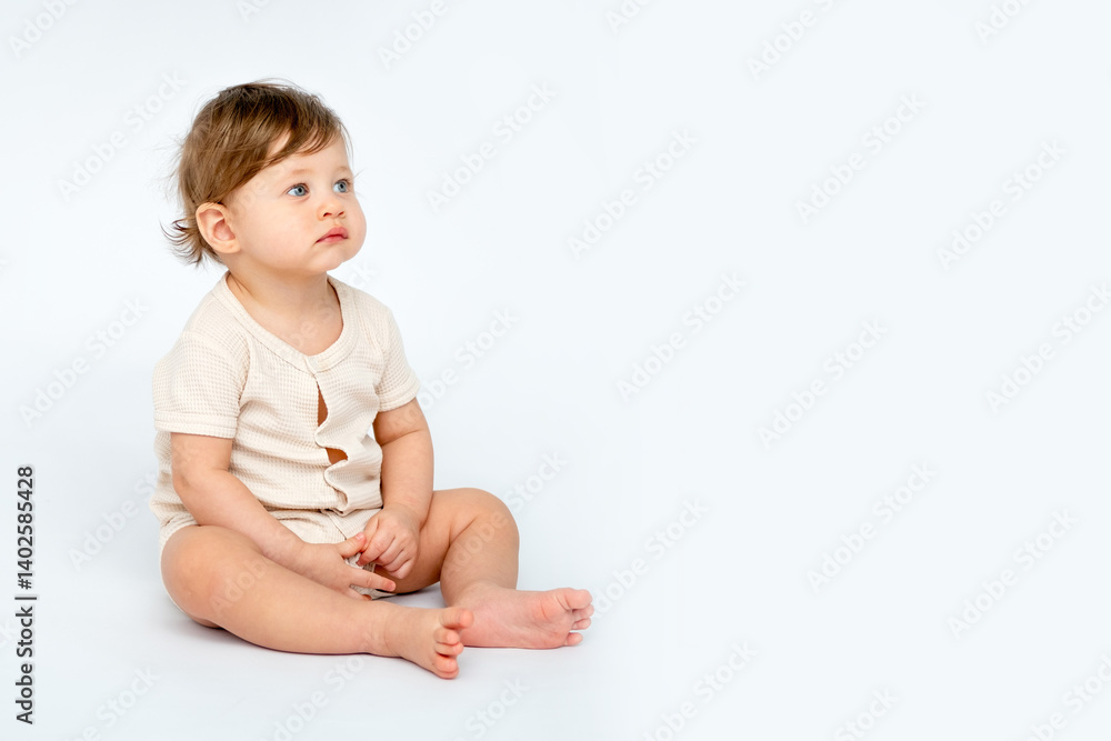 A baby boy is sitting on a white isolated background with a place for text in light clothes. A small happy child, space for text
