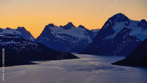 A serene and majestic alpine scene featuring a glacial lake at sunset with snow-capped mountains reflected in its calm waters.