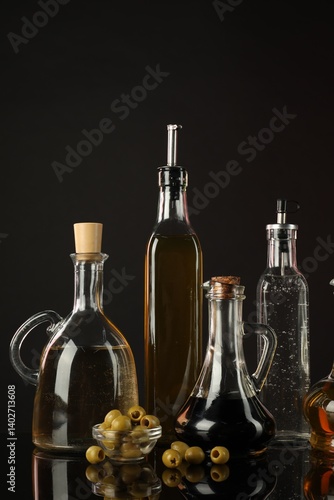 Fototapeta Naklejka Na Ścianę i Meble -  Salad dressings and olives on mirror surface against black background