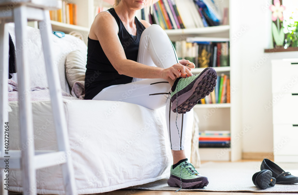fit woman at home taking her running shoes getting ready for a run