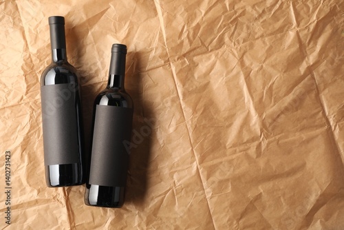 Bottles of wine on parchment paper, flat lay. Space for text