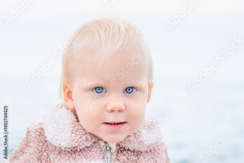 Obraz na płótnie A delightful and charming toddler is gazing intently at the camera, set against a beautiful scenic water backdrop w salonie