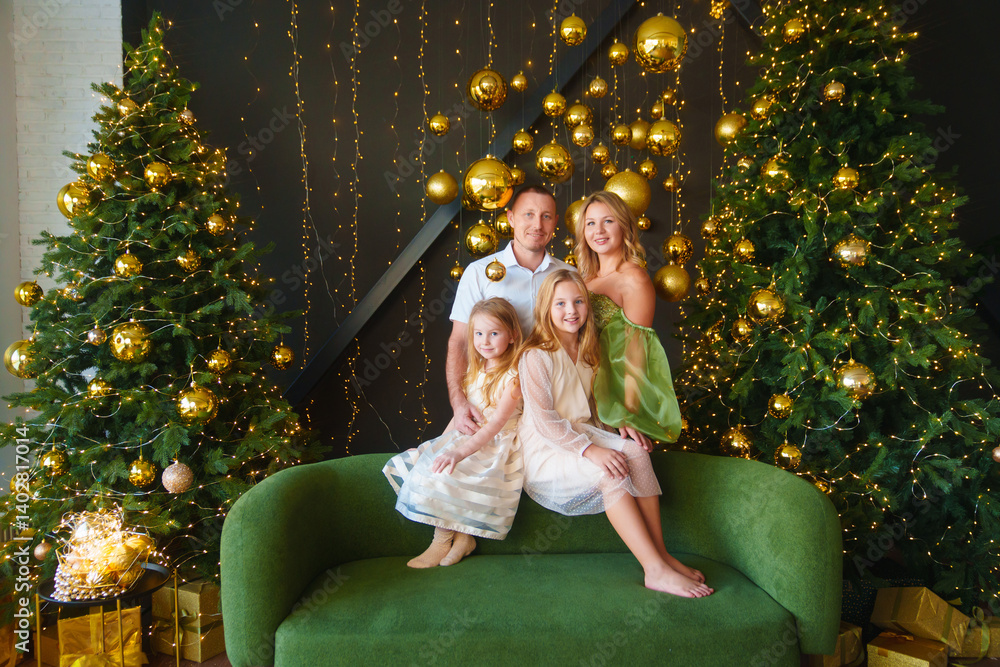 A happy family in elegant clothes on a green sofa at the Christmas tree.