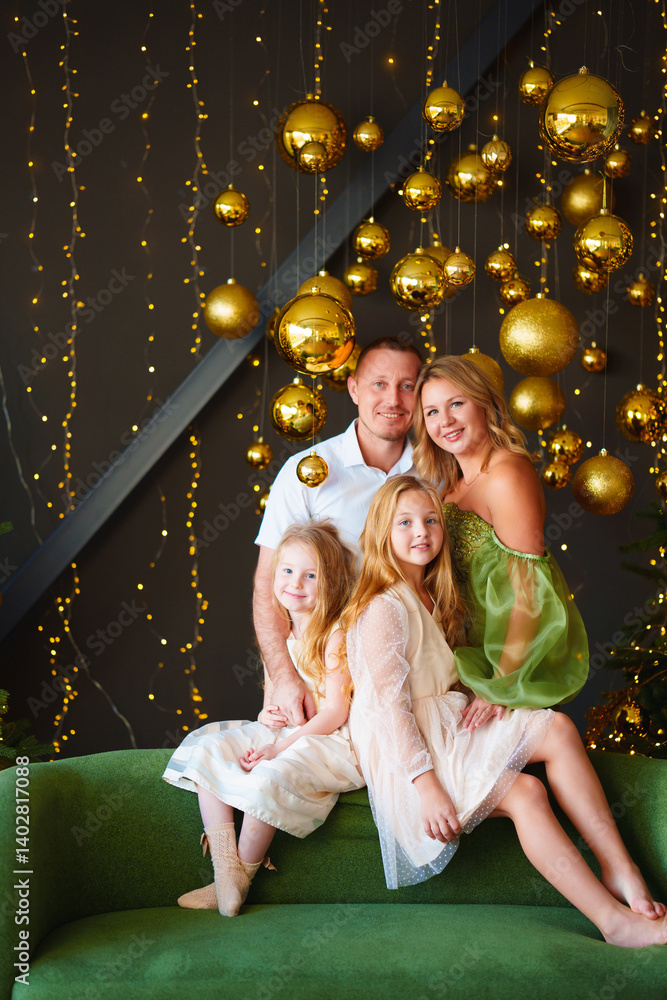 A happy family in elegant clothes on a green sofa at the Christmas tree.