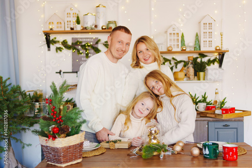 A beautiful and happy family at the Christmas tree at home in the kitchen.