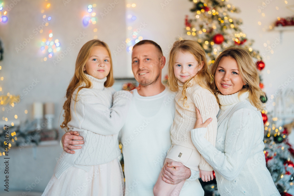 A beautiful and happy family in cozy sweaters at the Christmas tree.