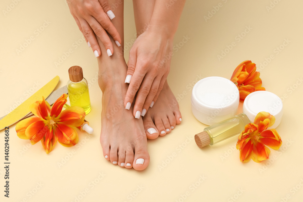 Woman showing neat toenails and fingernails after pedicure and manicure procedures, tools, cosmetic products and flowers on beige background, closeup