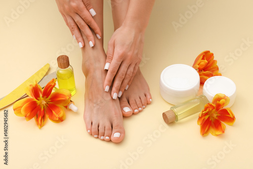 Obraz na płótnie Woman showing neat toenails and fingernails after pedicure and manicure procedures, tools, cosmetic products and flowers on beige background, closeup w salonie