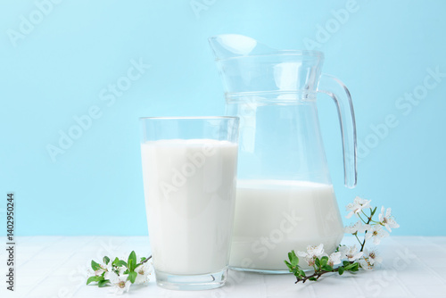 Fotografía Fresh milk and blossoms on white table against light blue background