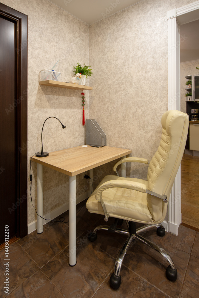 Apartment interior. Leather chair near a small desk. Desk lamp on the desk. Shelf on the wall. Compact work area in the hallway of a small apartment. Writing corner. Home mini-office.