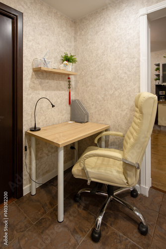 Obraz na płótnie Apartment interior. Leather chair near a small desk. Desk lamp on the desk. Shelf on the wall. Compact work area in the hallway of a small apartment. Writing corner. Home mini-office. w salonie