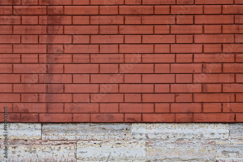 Obraz na płótnie Red brick wall texture. The decorative plaster imitating a bricklaying and the socle revetted with a stone. Background brickwork. w salonie