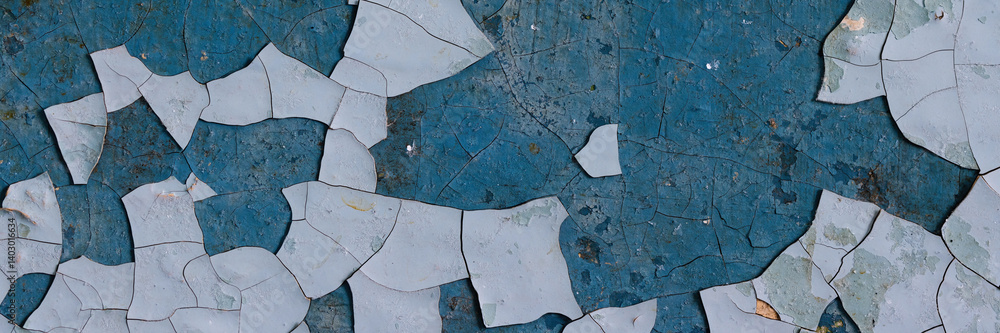 Peeling paint on the wall. Panorama of a concrete wall with old cracked flaking paint. Weathered rough painted surface with patterns of cracks and peeling. Panoramic texture for background and design.