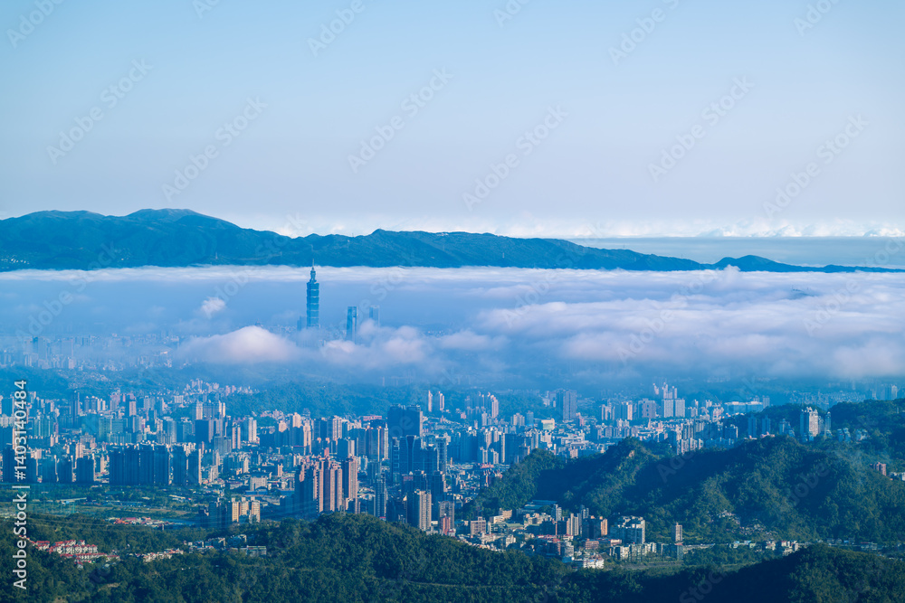 Fototapeta premium A serene spring morning view of Taipei from Lion Head Mountain. White clouds drift over the city skyline, featuring prominent high-rise buildings. 