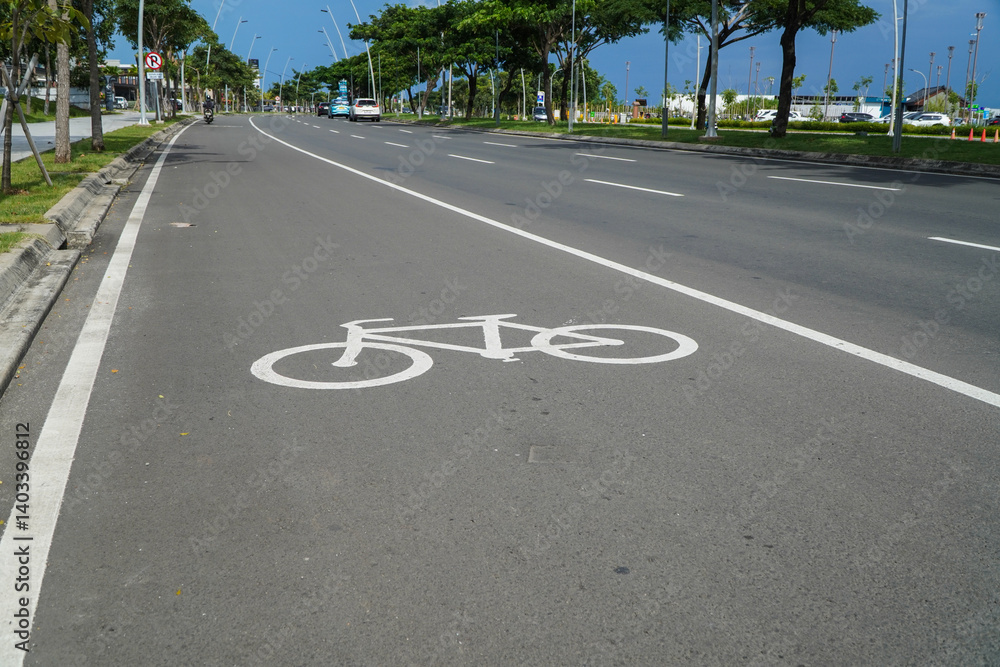 Obraz premium Bicycle Lane Marking on Asphalt Road in Urban Environment with Greenery and Blue Sky