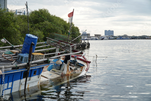 Sinking Weathered Fishing Boat Docked at a Harbor with Reflections in Calm Water under Cloudy Sky