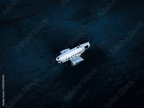 Obraz na płótnie On Iceland’s stark black sands, a stranded DC-9 wreck stands out. The figure perched atop its fuselage adds a sense of scale, so seamlessly blending human curiosity with nature's rugged, moody allure. w salonie