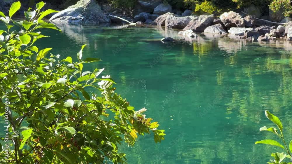 Turquoise water of the Baduk mountain lakes in a mountain valley in the mountains of the North Caucasus, on a sunny summer day. The blue sky and mountain peaks are reflected in the lake. 4К Turquoise water of the Baduk mountain lakes in a mountain valley in the mountains of the North Caucasus, on a sunny summer day. The blue sky and mountain peaks are reflected in the lake. 4К