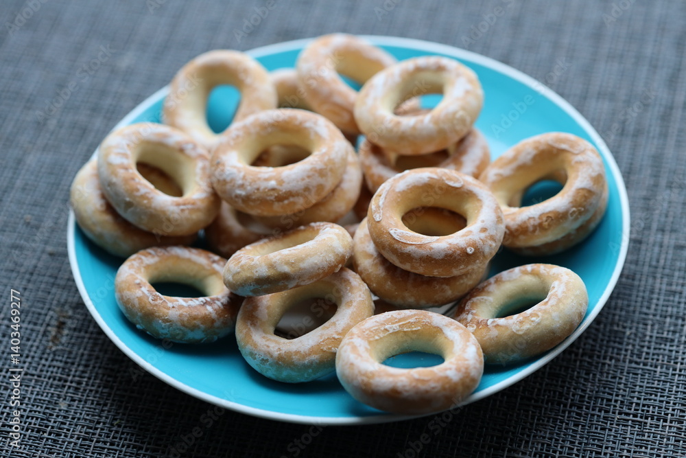 A blue plate filled with donuts covered in powdered sugar, perfect for a bakery display or dessert table.