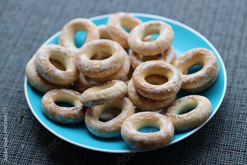 A blue plate filled with donuts covered in powdered sugar, perfect for a bakery display or dessert table.