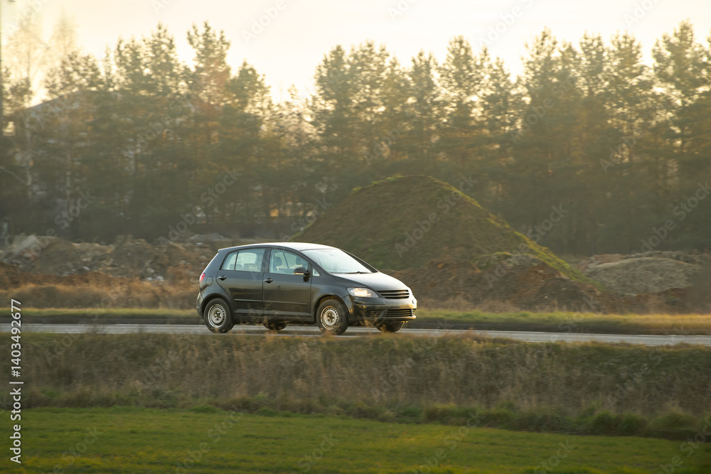 Compact hatchback driving on country road