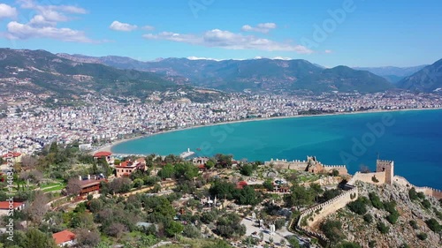 Magnificent aerial view of the fortress and the opening panorama of the Mediterranean coast and the beach line of Alanya, Türkiye. Filmed with a drone.