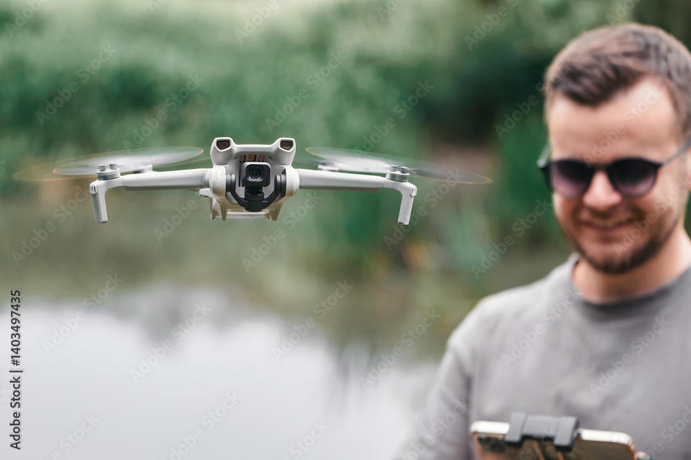 Man wearing sunglasses flying drone by water