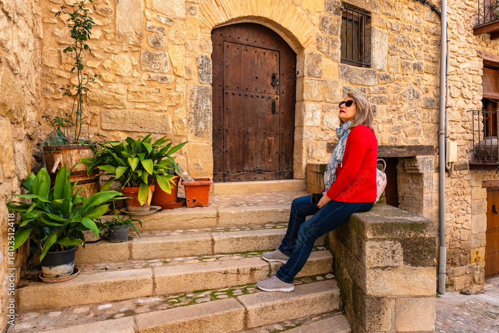 Tourist woman resting at the foot of a medieval house while enjoying the views of the village of Valderrobres, Teruel