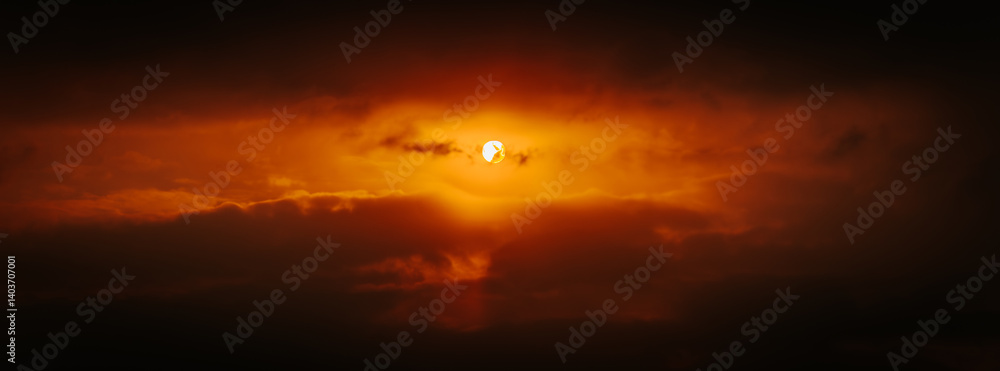Fototapeta premium A partial solar eclipse glows through dramatic red-orange clouds, casting an intense and surreal light in a dark sky. Includes ample copy space.