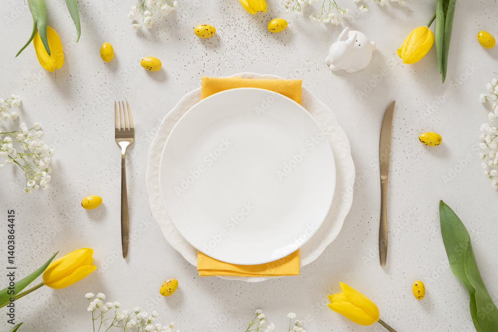 Easter table setting with spring, yellow tulips, empty white plates, bunny, eggs on white background. Happy Easter celebration. Copy space. View from above.