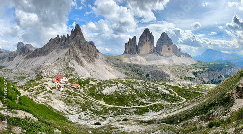 Famous mountain range Tre Cime di Lavaredo with surrounding peak monte paterno and mountain hut antonio locatelli in foredground at noon