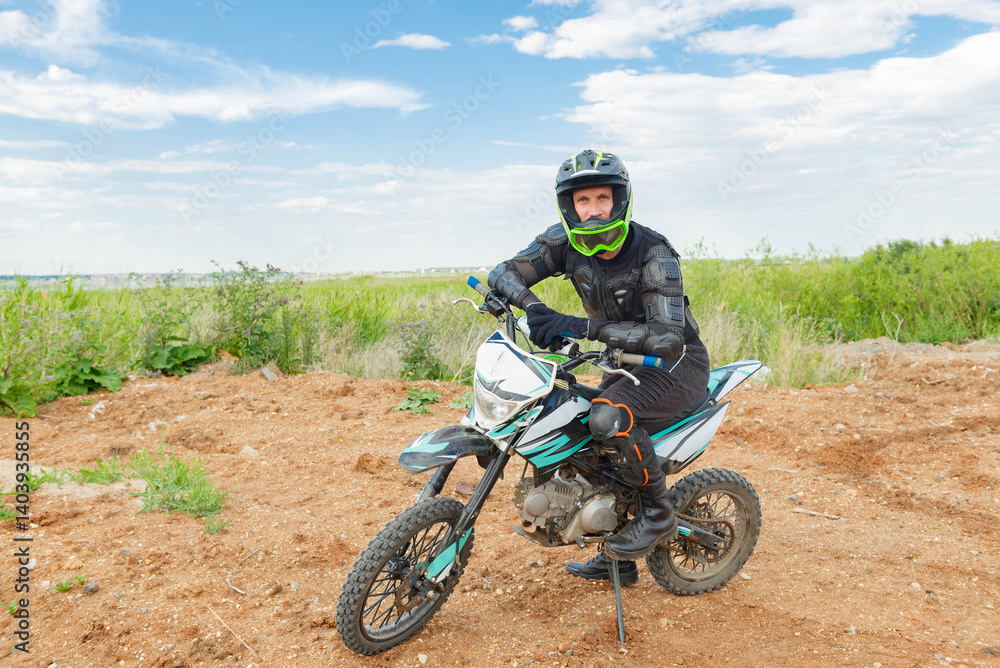 A man in motorcycle equipment sits on an enduro motorcycle. A man in motorcycle equipment sits on an enduro motorcycle.