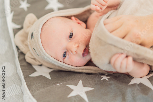 Obraz na płótnie A newborn baby lies wrapped in a soft towel after a warm bath, enjoying a moment of comfort and relaxation. A heartwarming scene symbolizing baby care, hygiene, and the soothing bond of early w salonie