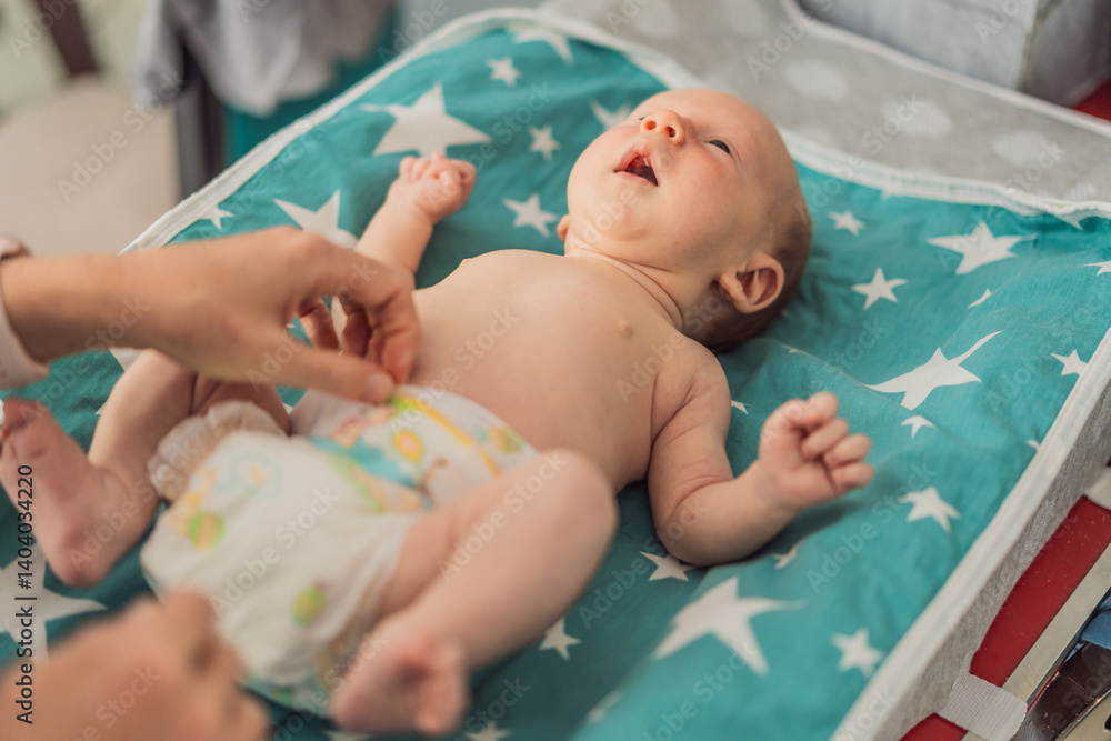 Young mother changing her baby diaper at home. Caring mom practicing hygiene routine with newborn child. Parenthood, baby care, and early motherhood concept