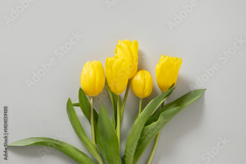 Bouquet of Spring yellow tulips on pastel neutral gray background. Top view. Happy holiday. Greeting card for Mother day or romantic anniversary.