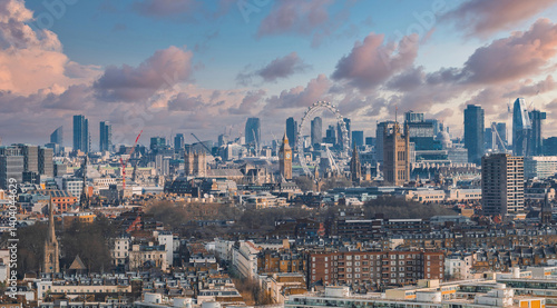 Aerial view of London showcasing the London Eye, Big Ben, and the Houses of Parliament, with modern skyscrapers and urban development in the background.