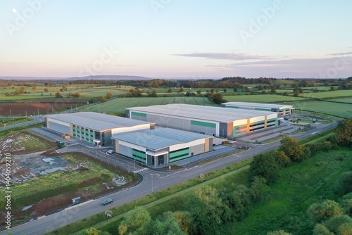 Aerial View of Modern Industrial Warehouse Complex in Green Countryside at Sunset – Commercial Buildings in Rural Setting