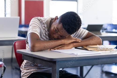 In school, student resting head on desk, feeling tired in classroom