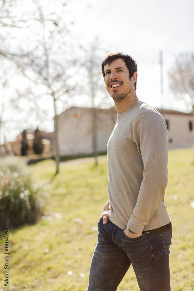 Relaxed man walking through a park with a soft smile, hands in pockets. Expresses ease, confidence and natural charm. Ideal for lifestyle, wellness or modern masculinity themes. Vertical, copy-space. Relaxed man walking through a park with a soft smile, hands in pockets. Expresses ease, confidence and natural charm. Ideal for lifestyle, wellness or modern masculinity themes. Vertical, copy-space.