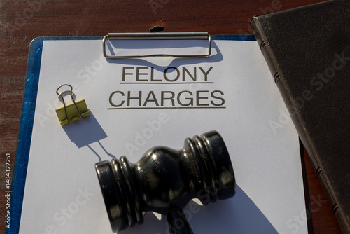 A felony charges paper secured in a clipboard, placed with a gavel resting on the desk, symbolizing serious criminal offenses and judicial authority.
