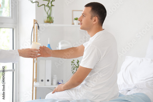 Male patient taking cup of ...
