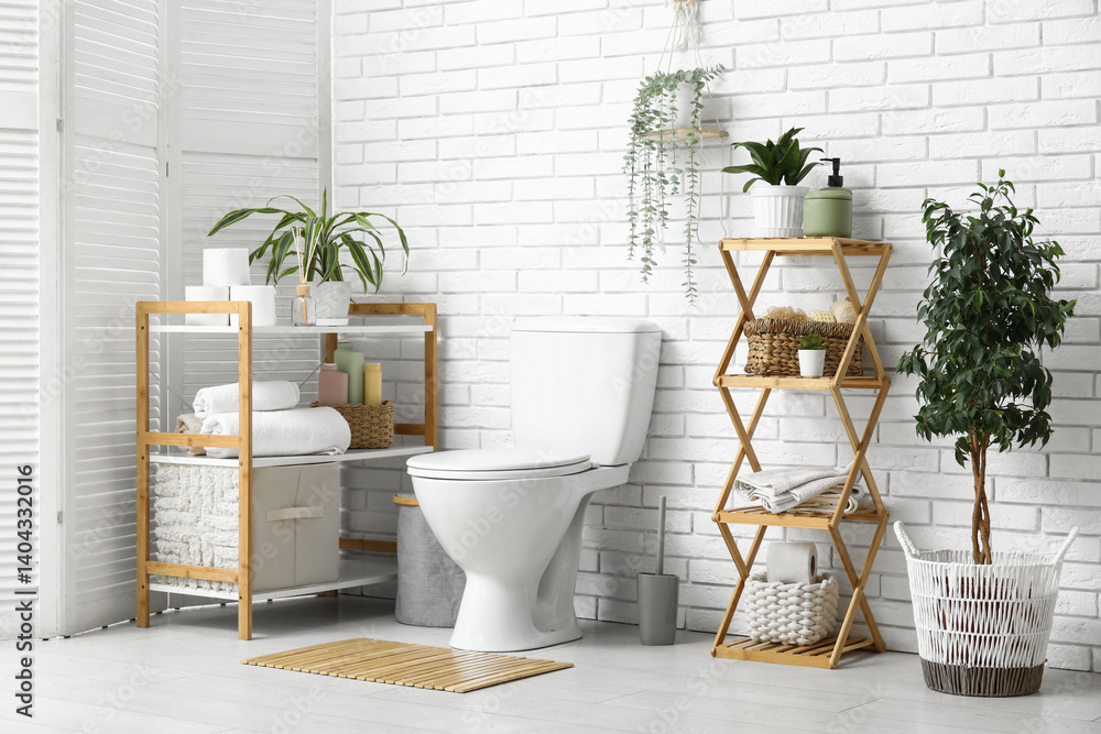 Interior of modern restroom with ceramic toilet bowl, houseplant and shelving unit near white brick wall